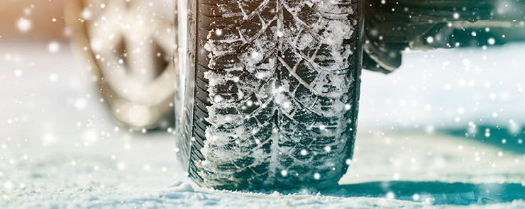 Close-up of car wheels rubber tires in deep winter snow. Transportation and safety concept.